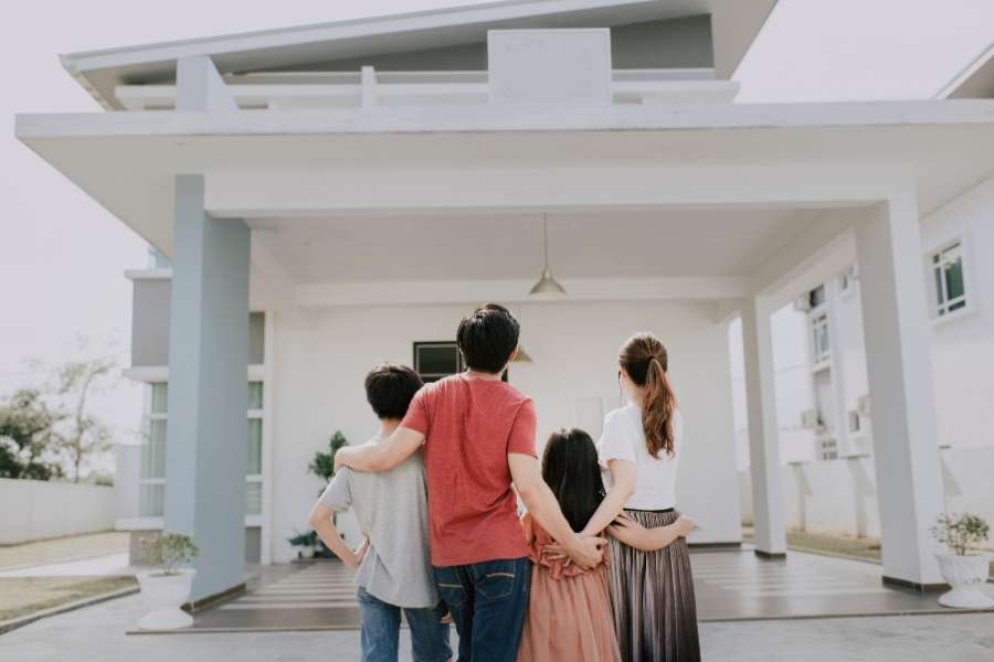 A family of four standing outside and looking up at their new move-in ready home.